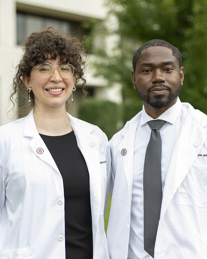 CMS students Angelica Arzuaga (left) and Kelly Harris in their white coats outside Rosalind Franklin University.